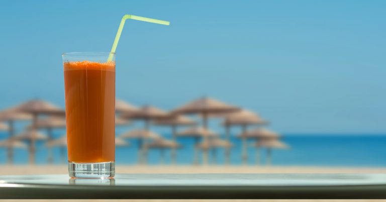 Ein Glas Karottensaft am Strand