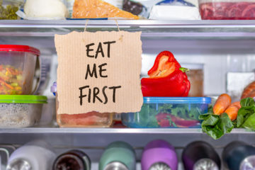 geöffneter Kühlschrank mit Lebensmitteln in Verpackungen und Tupperware