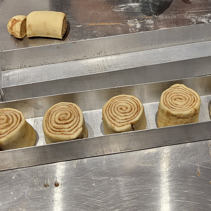 Zubereitung der Zimtschnecken: Die Rolle wird per Augenmaß in Stücke geschnitten.