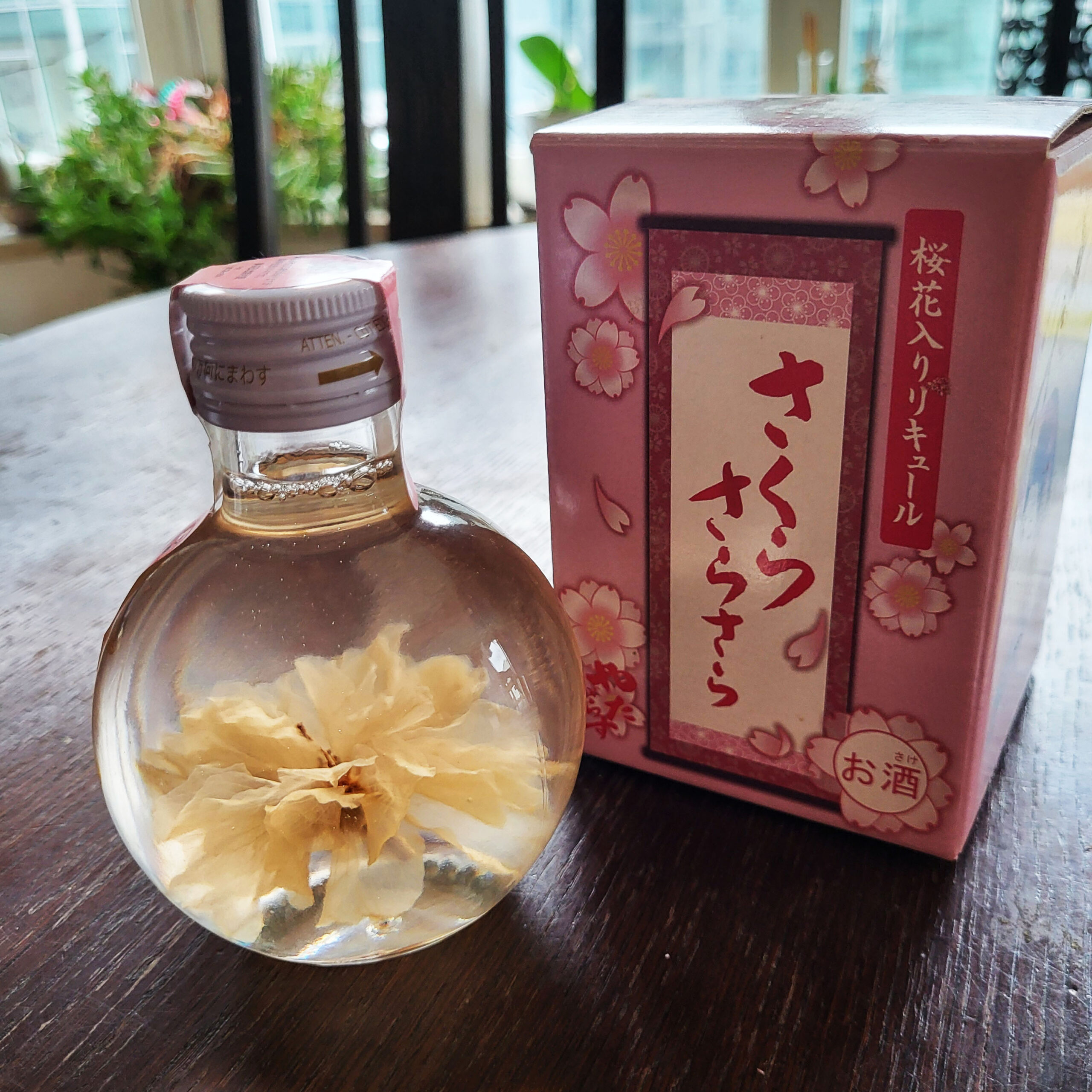 Japanischer Sakura-Likör in der Flasche mit Originalverpackung daneben.