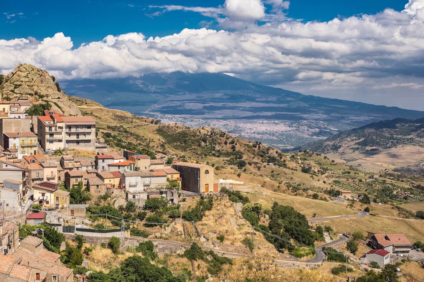 Die Stadt Cesaro im Vordergrund, die Wolken des Ätna-Vulkans verdecken ihren Gipfel im Hintergrund, die Stadt Bronte in der Mitte des Bodens. Sizilien, Italien.